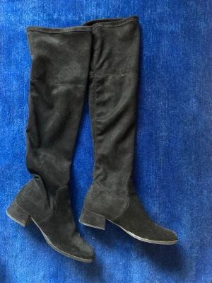 Svarta overknee stövlar från LC COBLER - Snygga svarta overknee stövlar från LC COBLER i storlek 40. Tillverkade i mockaimitation med bred klack och rundad tå. 