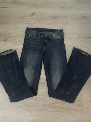Mörkblå bootcut jeans från Cheap monday - Säljer ett par mörkblå bootcut jeans med slitningar och lätt tvättade detaljer framtill. Jeansen har klassisk femficksmodell och normal midja. Perfekta för dig som gillar en avslappnad men ändå trendig look.