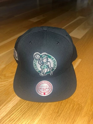 Mitchell & Nees boston Celtics keps(helt ny) - Säljer denna Mitchell & Nees keps då jag inte riktigt fått användning av den alls utan jag köpte den och testade den en gång men fick aldrig någon direkt användning utav den så den är helt ny och har till och med kvar formen i kepsen. Storlek 55-60 cm.