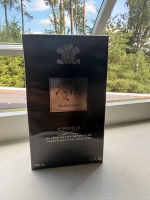 Creed Aventus Eau de Parfum 100 ml - Lyxig parfym från Creed, Aventus Eau de Parfum i svart och silver förpackning. Flaskan rymmer 100 ml och har en elegant design med metallisk etikett och klassisk logga. En ikonisk doft som passar dig som vill sticka ut.