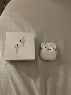 Apple AirPods med laddningsetui - Säljer ett par vita Apple AirPods med trådlöst laddningsetui. Snygg och stilren design i plast, perfekt för dig som vill ha smidiga hörlurar till mobilen. Kommer med originalförpackning och tillbehör.
