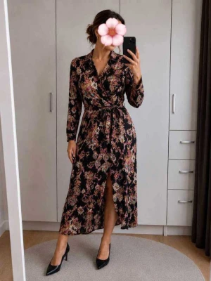 Blommig omlottklänning med knyt - Snygg långärmad omlottklänning med blommigt mönster i svart, rosa, beige och blå toner. Klänningen har knyt i midjan, v-ringning och slits framtill. Perfekt för dig som gillar färg och mönster. Materialet känns mjukt och följsamt.