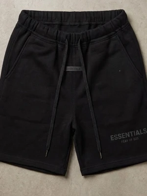 Svarta shorts från Essentials - Säljer ett par svarta shorts från Essentials Fear of God med långa snören i midjan och diskret logga på benet. Shortsen har elastisk midja och sidofickor, perfekta för en avslappnad och trendig look.