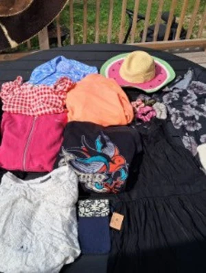Blandade kläder och accessoarer! - Parti med kläder och accessoarer. Innehåller en svart fluffig tröja, en röd- och vitrutig topp, en blå- och vitmönstrad blus i viskos, en vit spetströja, en svart långärmad tunika med trumpetärm, en svart mönstrad klänning med trumpetärm, en svart klänning med dragkedja och prickig mesh från Carlings, en orange fleecetröja (finns fläckar), en rosa hoodie från Nike, en svart munkjacka med broderad svala från Carlings (nopprig), en vit kort kofta (finns fläckar), en stråhatt med vattenmelonmotiv (