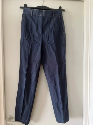 Mörkblå raka jeans med hög midja - Snygga mörkblå mjuka jeans med raka ben och hög midja. Jeansen har klassiska fickor fram och bak, bälteshällor och kontrastsömmar. Materialet är denim och passformen är avslappnad men ändå stilren.