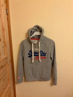 The real Superdry Hoodie  - En väldigt snygg The real Superdry Hoodie. I väldigt bra skick skulle säga 8/10. | Storlek M                Hör av er vid mera frågor/bilder 🙌🤝