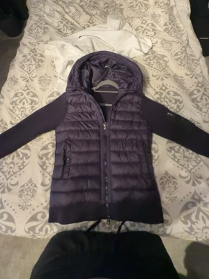 Mörklila dunväst med huva från Moncler - Säljer denna marinblåa moncler cardigan då den är för stor på mig o bara legat i min garderob. Fungerande NFC-tagg, o andra kännetecken som loggor osv. Nyligen köpt, med prislapp men borttagen då jag trodde den skulle passa fint