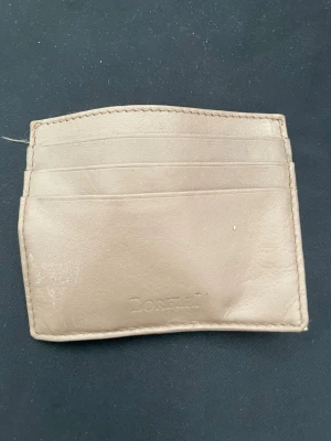 Beige kortfodral i läder - Säljer ett stilrent beige kortfodral i äkta läder med flera fack för kort. Enkel och smidig design som passar perfekt i fickan. Perfekt för dig som vill ha koll på dina kort utan att bära en stor plånbok.