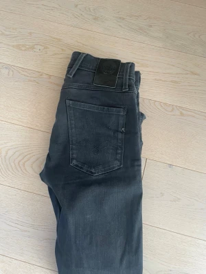 Svarta slim fit jeans - Snygga svarta slim fit jeans med klassisk femficksdesign och diskreta sömmar på bakfickan. Jeansen har normal midja och raka ben, perfekta för en clean och stilren look. Materialet känns mjukt och stretchigt för extra komfort.