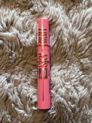 Sky High rosa mascara - Säljer en mascara i snygg metallicrosa hylsa med texten 'Sky High' i silver. Borsten är smal och flexibel, perfekt för att få långa och separerade fransar. Modern design som sticker ut i sminkväskan.