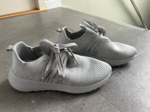 Grå sneakers från ARKK Copenhagen - Snygga grå sneakers från ARKK Copenhagen med stickad ovandel och breda matchande skosnören. Skorna har en chunky vit sula och modern design som passar perfekt till streetwear. Materialet är mesh-liknande och ger en sportig vibe.