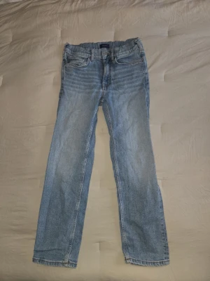 Ljusblå raka jeans i bomull - Säljer ett par ljusblå Gant jeans med rak passform. Klassisk femficksmodell med knapp och dragkedja i gylfen. Jeansen är tillverkade i bomull och har kontrastsömmar. Perfekta för dig som gillar en enkel och tidlös stil.