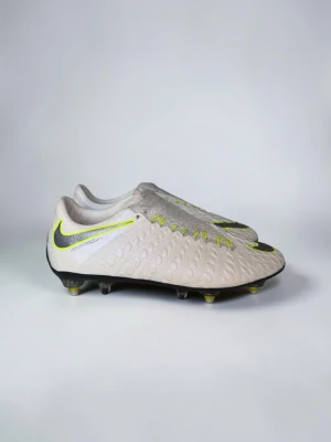 Nike Hypervenom Phantom III “Elite Anti-Clog” – i toppskick! - Storlek: 41  Vitt utförande med signaturens flytande svarta/limegröna detaljer på ovanlägget. Utrustad med skruvdubbar (SG) med guldiga dubbnycklar – perfekt för mjukare underlag. Dynamic Fit-kragen ger sockliknande passform runt ankeln för extra stöd i varje rörelse.  ✅ Nyskick – använda ett fåtal gånger, inga större slitagemärken ✅ Storlek 41  ✅ Äkta vara  Perfekt par för dig som vill ha premiumskor i toppskick kom gärna med bud! Orginalskosnören finns bara avtagna