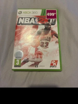 NBA 2K11 Xbox 360 spel - NBA 2K11 till Xbox 360, basketspel med Michael Jordan på omslaget. Spelet kommer i ett grönt plastfodral och skivan har samma design som omslaget. Perfekt för dig som gillar sportspel och basket.