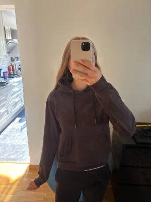 Mörkbrun hoodie med huva - Säljer en enkel och stilren mörkbrun hoodie med huva och dragsnören. Hoodien har en stor magficka framtill och ribbade muddar vid ärmslut och nederkant. Inte använd mycket, säljer pga att den börjar bli för liten. Vet inte exakt märket men den är köpt på Gekås, Ullared.
