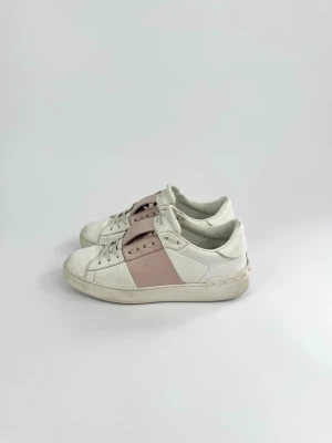 Valentino Open Sneaker Dam - Valentino open sneakers i rosa och vit. Märke: Valentino  Garavani Storlek: 37 o 1/2  Färg: Vit och rosa Skick: Använda med slitage på vissa ställen, men mycket kvar att ge, se bilder. Beskrivning: Endast skor tillkommer. 
