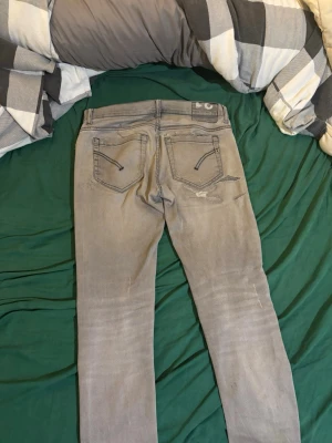 Grå slita slim fit  - Snygga grå slim fit jeans med slitningar och trasiga detaljer på framsidan. Jeansen har klassisk femficksdesign och smal passform. Perfekta för en avslappnad och trendig look.