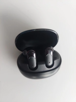 Svarta trådlösa in-ear hörlurar - Säljer ett par stilrena svarta trådlösa in-ear hörlurar med laddningsetui. Hörlurarna har en blank finish och modern design, perfekta för musik och samtal på språng. Kompakt fodral som är lätt att ta med sig överallt.