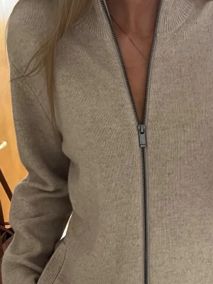 Unisex kofta - Snygg beige ziptröja med hög krage och långa ärmar. Tröjan har en rak passform och ribbade muddar vid ärmslut och hals. Den är köpt på herravdelningen men tycker passar när man viker upp kanten eller bara oversized. Passar även herr. Storlek M (herr M). Använd ca 3 tillfällen❣️