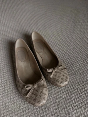Ballerinaskor - Säljer ett par beige ballerinaskor med små blommönster och söt rosett framtill. Lite vintage stil på dem, så snygga till jeans eller vad som🥰🥰 Vet tyvärr inte vart de är ifrån då de är köpta på vinted🩷Jättefint skick! Kommer inte till användning så mycket därför säljer jag🫶🏼