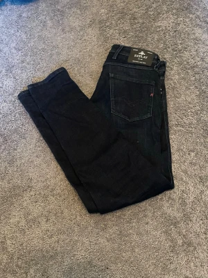 Mörkblå slim fit jeans från Replay - Snygga mörkblå slim fit jeans från Replay med klassisk femficksdesign och silverfärgade detaljer. Jeansen är modellen Anbass 