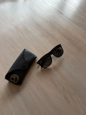 Svarta Ray-Ban solglasögon Boyfriend - Klassiska svarta Ray-Ban Boyfriend solglasögon med mörka glas och stilren design. Bågarna är i svart plast och kommer med original Ray-Ban-fodral. Perfekta för att lyfta din look med en tidlös accessoar.