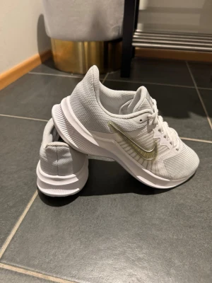 Nike Downshifter i storlek 40 - Nästan helt nya - Säljer ett par vita Nike Downshifter damskor (artikelnummer: CW3413-100) i storlek 40.  Skorna är i mycket fint skick och har endast använts en gång. De är lätta, bekväma och luftiga och passar perfekt för promenader, träning eller vardagsbruk. Säljs på grund av att de inte kommer till användning.