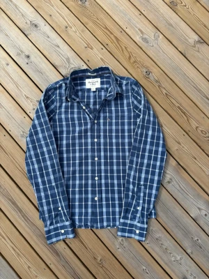 Abercrombie & Fitch skjorta ~ Sällsynt  - Säljer denna Abercrombie & Fitch skjorta i mycket bra skick och som är sällsynt så därmed väldigt eftertraktad. Skjortan har en defekt som ni ser på bild 4 men syns inte vid användning. Storlek L. Passar perfekt för dig som är mellan 180-185! Hör av er vid frågor eller minsta fundering 🙌  Längd: 70 cm  Bred: 51 cm  Ärm: 71,5 cm