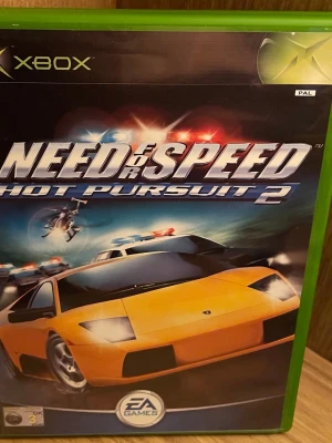 Need for Speed Hot Pursuit 2 Xbox - Need for Speed Hot Pursuit 2 till Xbox bjuder på fartfyllda polisjakter, supersportbilar och spännande racingbanor. Omslaget visar en gul sportbil och polisbilar i full action. Perfekt för dig som gillar adrenalinfyllda bilspel och klassiska racingupplevelser. Perfekt Skick
