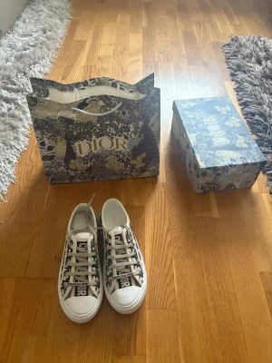 Dior Oblique låga sneakers - Snygga låga sneakers från Dior med det klassiska Oblique-mönstret i svart och vitt. Skorna har vita snören, gummisula och detaljer med 'Christian Dior' på plösen och sidan. Perfekta för dig som vill ha en exklusiv och trendig look.