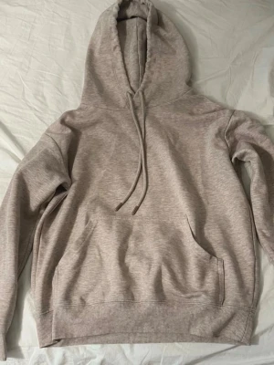 Beige hoodie  - Säljer en beige hoodie. Hoodien har en klassisk huva med dragsnören, magficka och ribbade muddar vid ärmslut och nederkant. Materialet är mjukt och skönt bomullsblandat tyg.