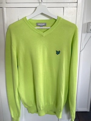 Ljusgrön stickad tröja Lyle & Scott - Stickad tröja i ljusgrönt från Lyle & Scott med V-ringning och deras klassiska logga broderad på bröstet. Tröjan har långa ärmar och ribbade muddar vid ärmslut och nederkant. Perfekt för dig som gillar färg och enkel stil. Skriv om ni har några frågor! 