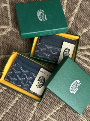 Blå kortfodral från Goyard - Säljer två stilrena blå kortfodral från Goyard med det klassiska mönstret i vitt och grått. Fodralen har flera fack för kort och är tillverkade i ett tåligt material med exklusiv känsla. Levereras i gröna presentaskar med Goyard-logga.