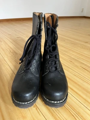 Metzeler Svarta höga läderkängor med snörning - Säljer ett par svarta höga boots i läder med grov sula och klassisk snörning framtill. Kängorna har en robust design och kontrastsöm längs sulan. Perfekta för dig som gillar en tuff och tidlös stil.