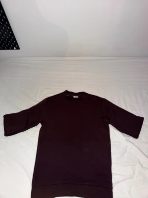 Svart t-shirt med trekvartsärm - En stilren brun  tröja  med trekvartsärm och rund hals. Modellen är rak och har en lite längre passform, perfekt för en avslappnad look. Tillverkad i mjukt material som känns skönt mot huden.