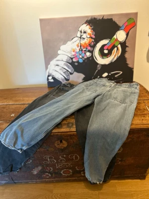 Två par jeans från D.M.D, strl 158 - Unika tvåfärgade jeans från D.M.D by denim daily i storlek 158. Ena benet är ljusblått och det andra är svart, vilket ger en cool och trendig look. Klassisk femficksmodell med resår i midjan och knappstängning. Perfekta för dig som vill sticka ut!