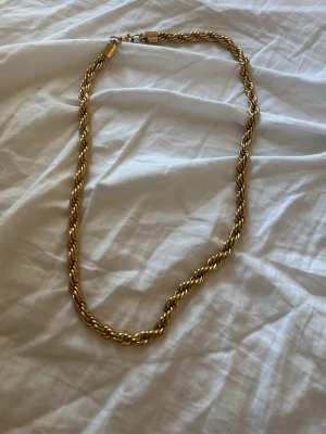 Guldfärgat tvinnat halsband - Säljer ett snyggt guldfärgat halsband med tvinnad kedja. Halsbandet har en klassisk karbinhake och känns både stilrent och trendigt. Perfekt för dig som gillar accessoarer med lite extra edge.