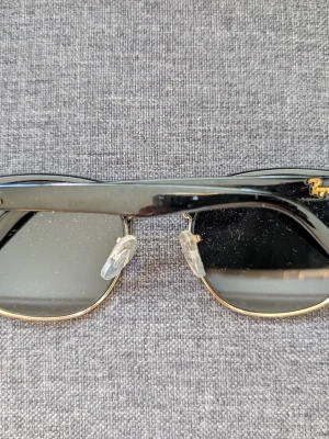 Ray-Ban Clubmaster solglasögon - Ray-Ban Clubmaster i svart och guld med gröngrå glas, den klassiska modellen. Inga repor på glasen, ser fräscha ut.