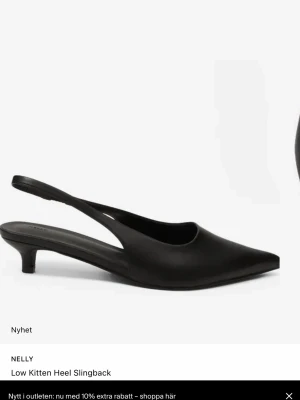 Populära Nelly klackar - Stilrena svarta pumps med spetsig tå och låg kitten heel. Skon har en öppen häl med slingback-rem och är tillverkad i ett slätt material som ger en elegant look. Perfekt för dig som gillar minimalistisk och trendig stil. Inte för hög klack för oss långa tjejer heller!