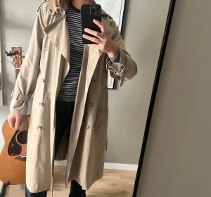 Beige klassisk trenchcoat med bälte från Zara  - Fin beige trenchcoat från Zara i storlek S. Är använd ett fåtal gånger. En knapp sitter dock lite löst på insidan - se bilder.