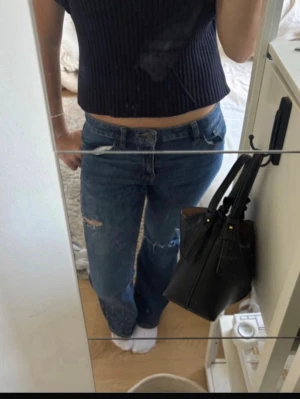 Blå bootcut jeans  - Säljer ett par blå jeans med utsvävning nere vid benen  och hål på låret och knät. Passar på mig som är 157