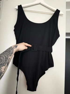 Ribbad Baddräkt m. Bälte - Cubus - Säljes då jag inte använder den längre! Men sitter supersnyggt och smickrande på kroppen då bältet i midjan är justerbart. 🌸 Du fäster bältet i två små hållare som finns på vardera sida av midjan, så du kan alltså välja om du vill ha bälte eller ej. Det finns även en liten flyttbar hållare som är till för att fästa resterande del av bältet, som blir hängande, i. 😊Använd ett par gånger men fortfarande i väldigt fint skick. Enda som är, är att storlekslappen inuti sitter lite löst. 😝