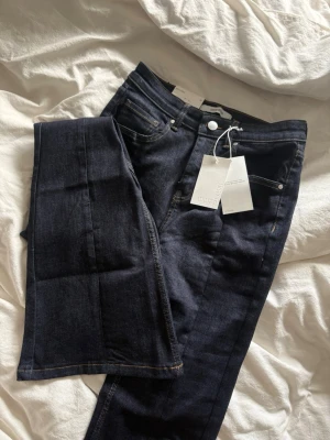 Mörkblå mid flare jeans - Snygga mörkblå jeans med mid flare passform och klassiska fem fickor. Jeansen har kontrastsömmar och en stilren look, materialet är stretchigt denim för extra komfort. Helt nya, nypris 500kr. Passar s/m
