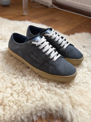 Saint Laurent Skor - Säljer nu mina Yves Saint Laurent Skor i blå mocka och beige/vita sulor. Skorna är i bra skick, och i storlek 41 eu herr. Skorna kan tvättas innan frakt 📦 🧼 Vid funderingar kontakta gärna!
