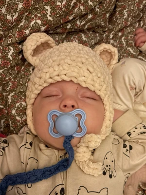 Beige virkad mössa med björnöron - Supersöt beige virkad mössa med björnöron och knytband. Mössan är gjord i ett tjockt, mjukt garn som känns fluffigt och varmt. Perfekt för att hålla huvudet varmt under kyliga dagar och ger en gullig look. Storlek 40/42 