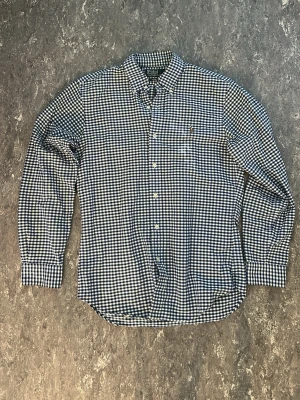 Blårutig skjorta från Polo Ralph Lauren - Klassisk blårutig skjorta från Polo Ralph Lauren med broderad logga på bröstet. Skjortan har lång ärm, knappar framtill och en mjuk krage. Perfekt för dig som gillar tidlös stil och vill ha något som funkar till många olika looks.