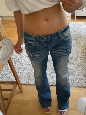 Blåa low waisted jeans med slitningar  - Säljer dessa blåa jeans från bongo❤️Säljer då de tyvärr inte passade..men de har inga defekter och är köpta på vinted! Är i storlek M och är bootcut✌️ Innerbenslängd: ca 82 cm midjemått: ca 39 cm