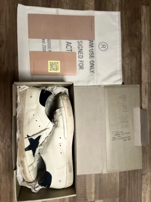 Golden Goose  - Golden Goose sneakers användaungefär 10 gånger därför jag säljer billigt. vitt läder med marinblå stjärna på sidan och marinblå hälparti. Klassisk låg modell med snörning och slitna detaljer för en cool, avslappnad look. Perfekta för dig som gillar streetstyle och unika detaljer.