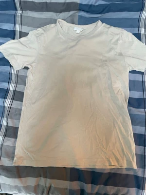 Beige basic t-shirt i bomull - En enkel och stilren beige t-shirt i mjuk bomull. T-shirten har klassisk passform med korta ärmar och rund halsringning. Perfekt att matcha med jeans eller shorts för en clean look.