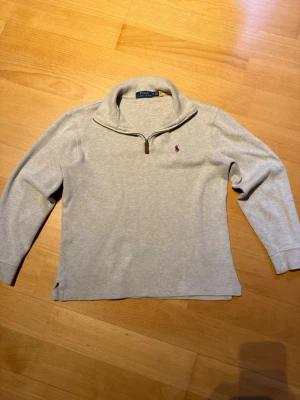 Ljusgrå stickad tröja Polo Ralph Lauren - Ljusgrå stickad tröja från Polo Ralph Lauren med halv dragkedja och liten broderad logga på bröstet. Priset är ej hugget i sten🙌